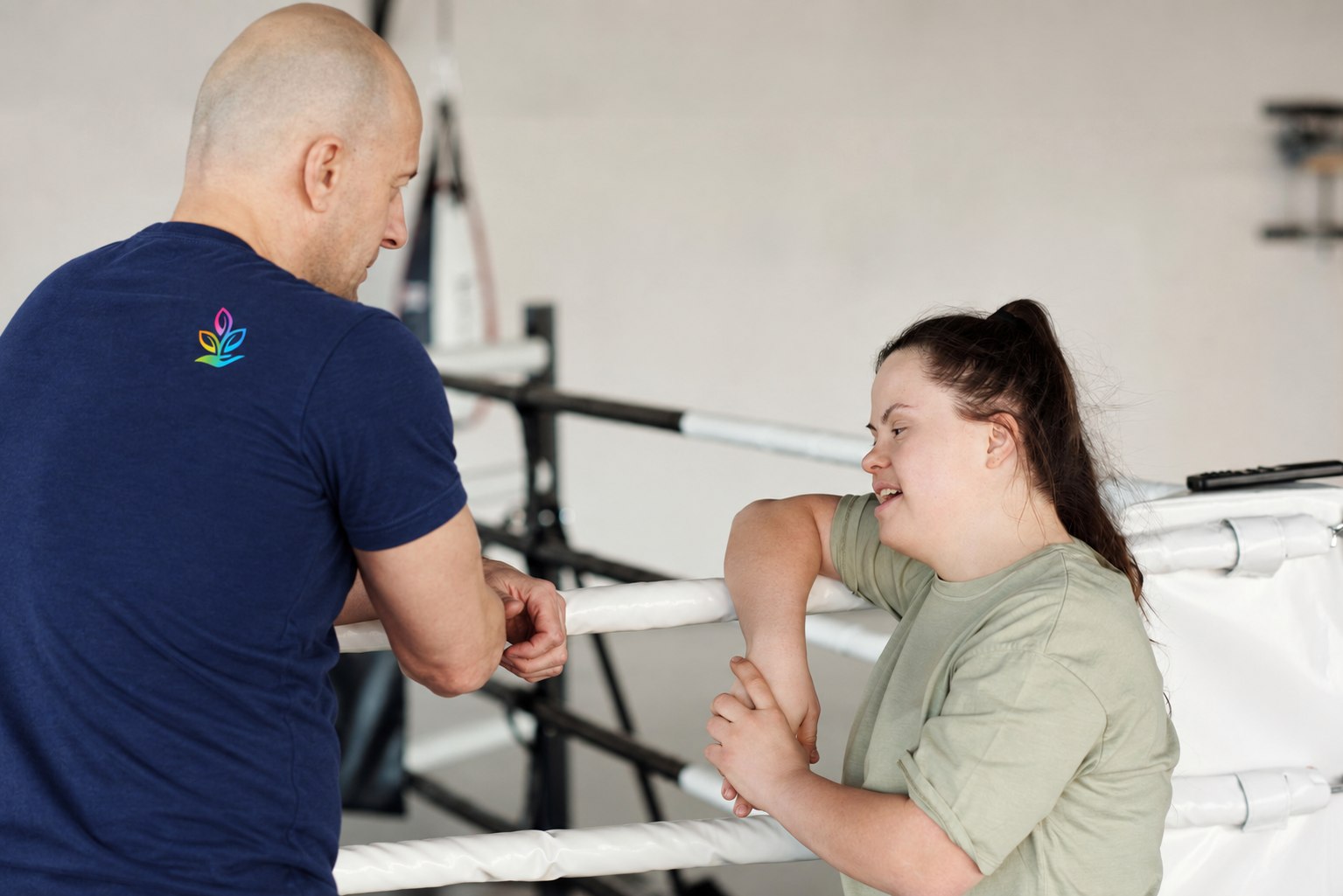 Illustrative stock photo of a support worker speaking with a young woman with Down syndrome during an exercise session